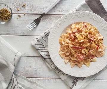 Farfalle com creme de parmesão, speck e pistache