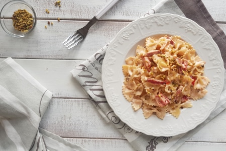 Farfalle com creme de parmesão, speck e pistache