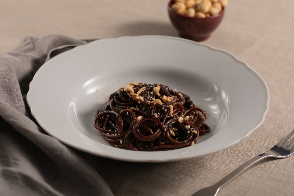 Spaghetti com creme de alho negro, alcaçuz e avelãs