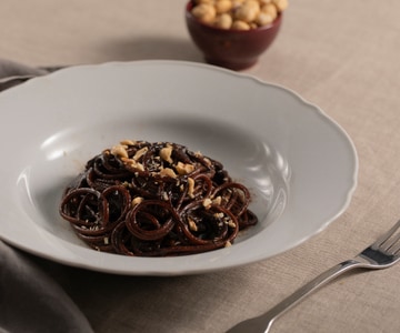 Spaghetti com creme de alho negro, alcaçuz e avelãs