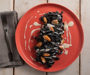 Tagliatelle ao negro de sépia com pecorino, mexilhões e bacon