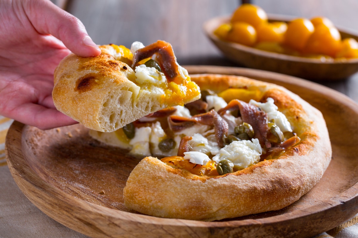 Pizza com tomatinhos amarelos, anchovas e alcaparras