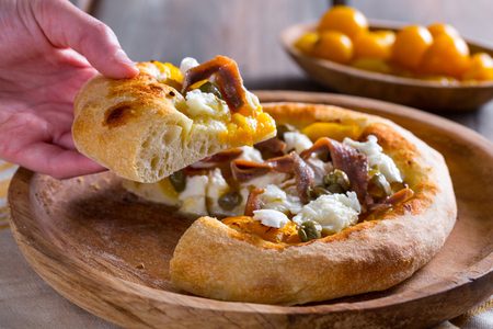 Pizza com tomatinhos amarelos, anchovas e alcaparras