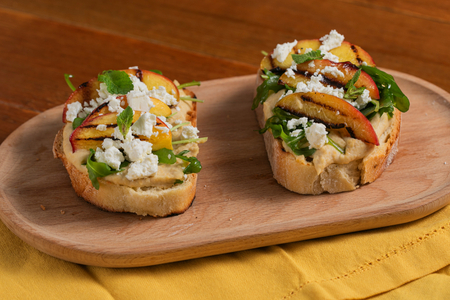 Torrada com homus, pêssegos grelhados, feta e rúcula