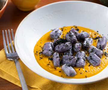 Nhoque de batata roxa com creme de abóbora e couve