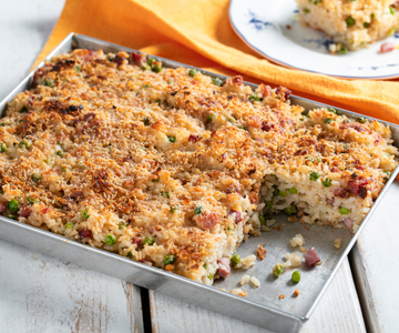 Arroz de forno com queijo derretido, ervilhas e speck