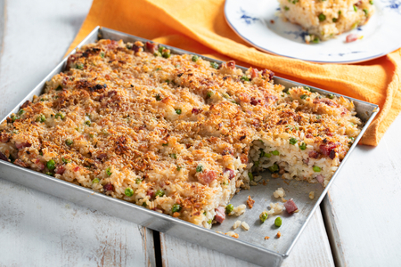 Arroz de forno com queijo derretido, ervilhas e speck