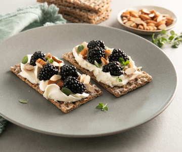 Fatias crocantes com creme de queijo e mel, amoras e amêndoas tostadas