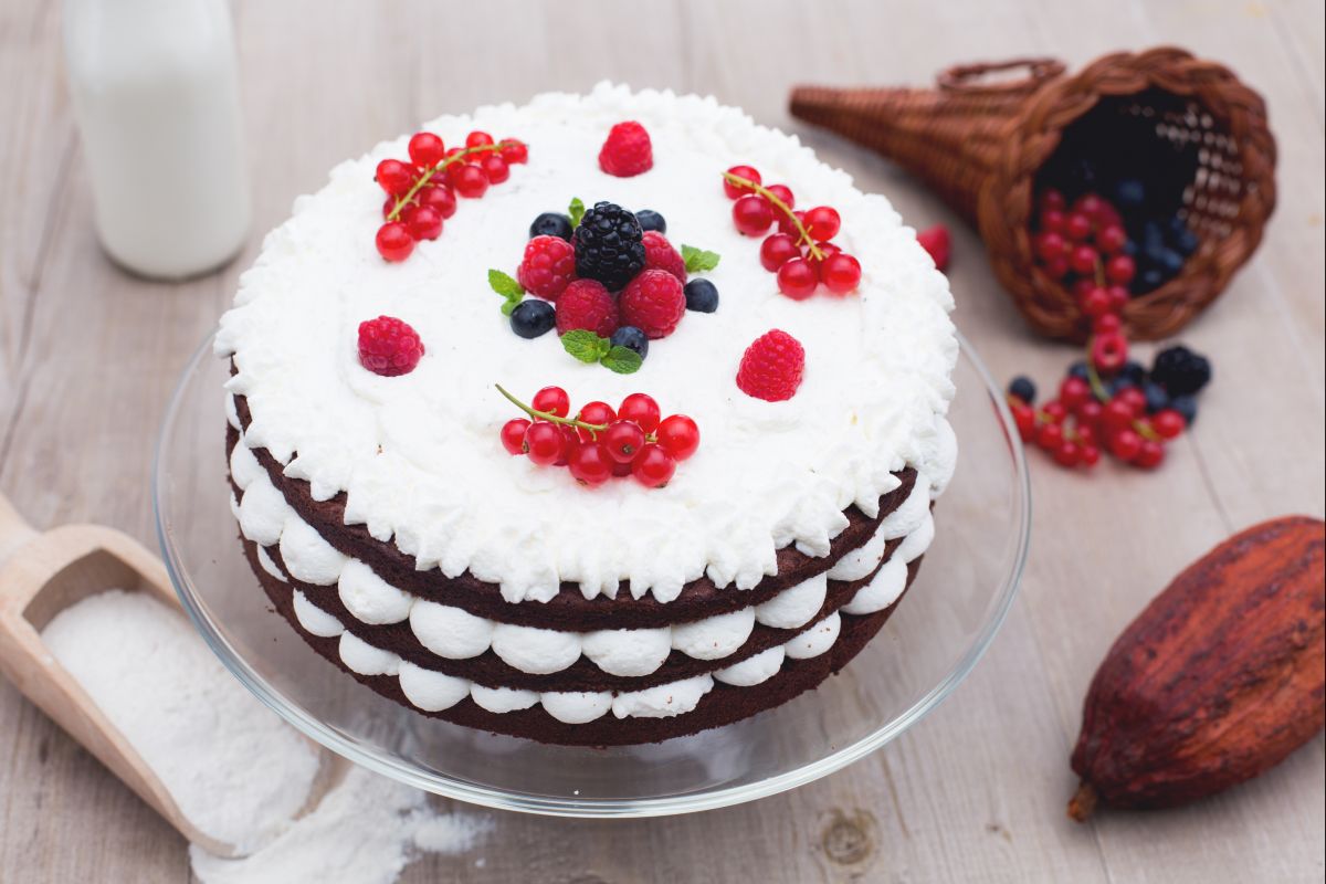 Bolo de camadas de chocolate com creme de leite e frutas vermelhas